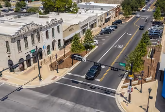 Bird’s-eye view of a street intersection in a small town with parked cars and historic buildings.