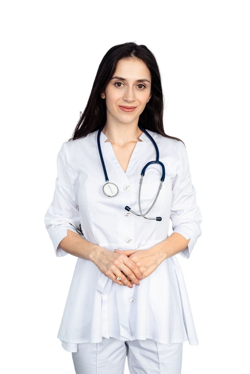 Female doctor wearing white coat with stethoscope around her neck, standing with hands clasped.