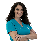 Smiling female healthcare professional in teal scrubs with folded arms on a white background.