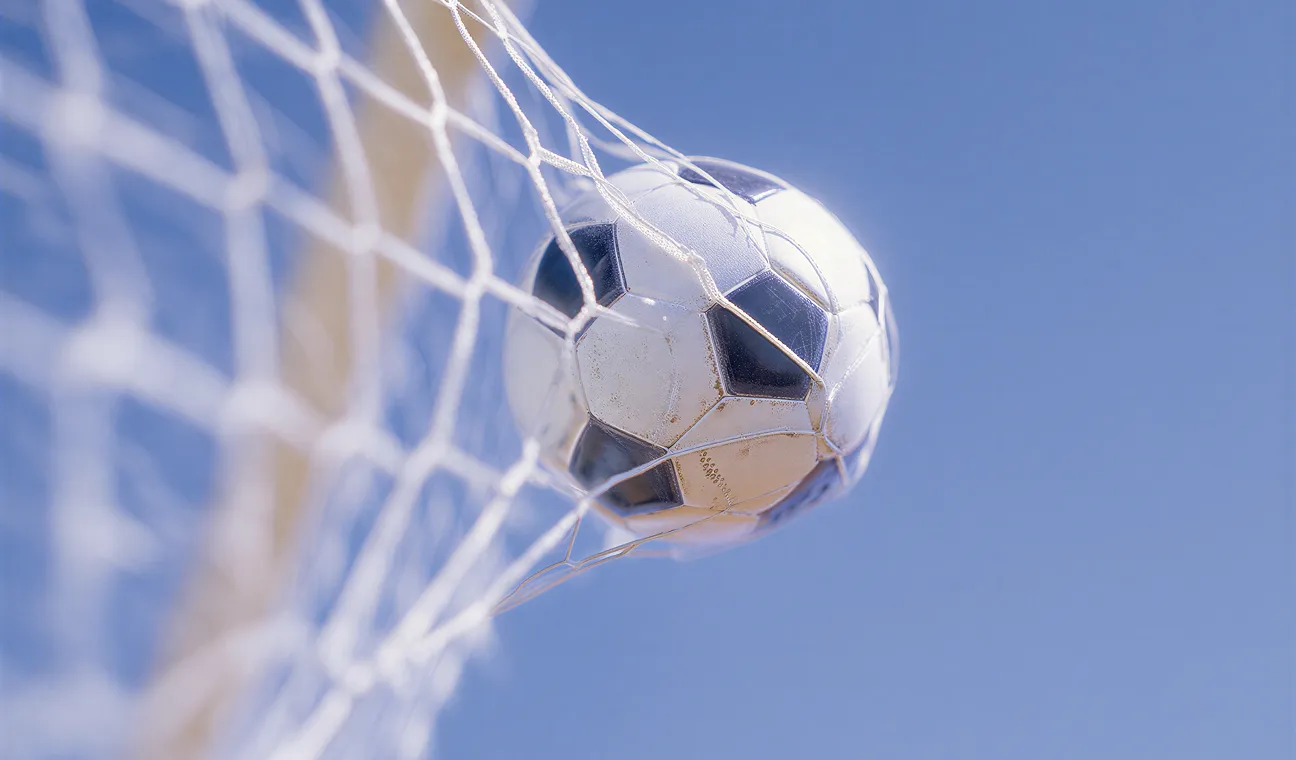 Soccer ball flying into a net against a blue sky