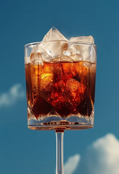 Glass of iced cola with a straw against a blue sky background