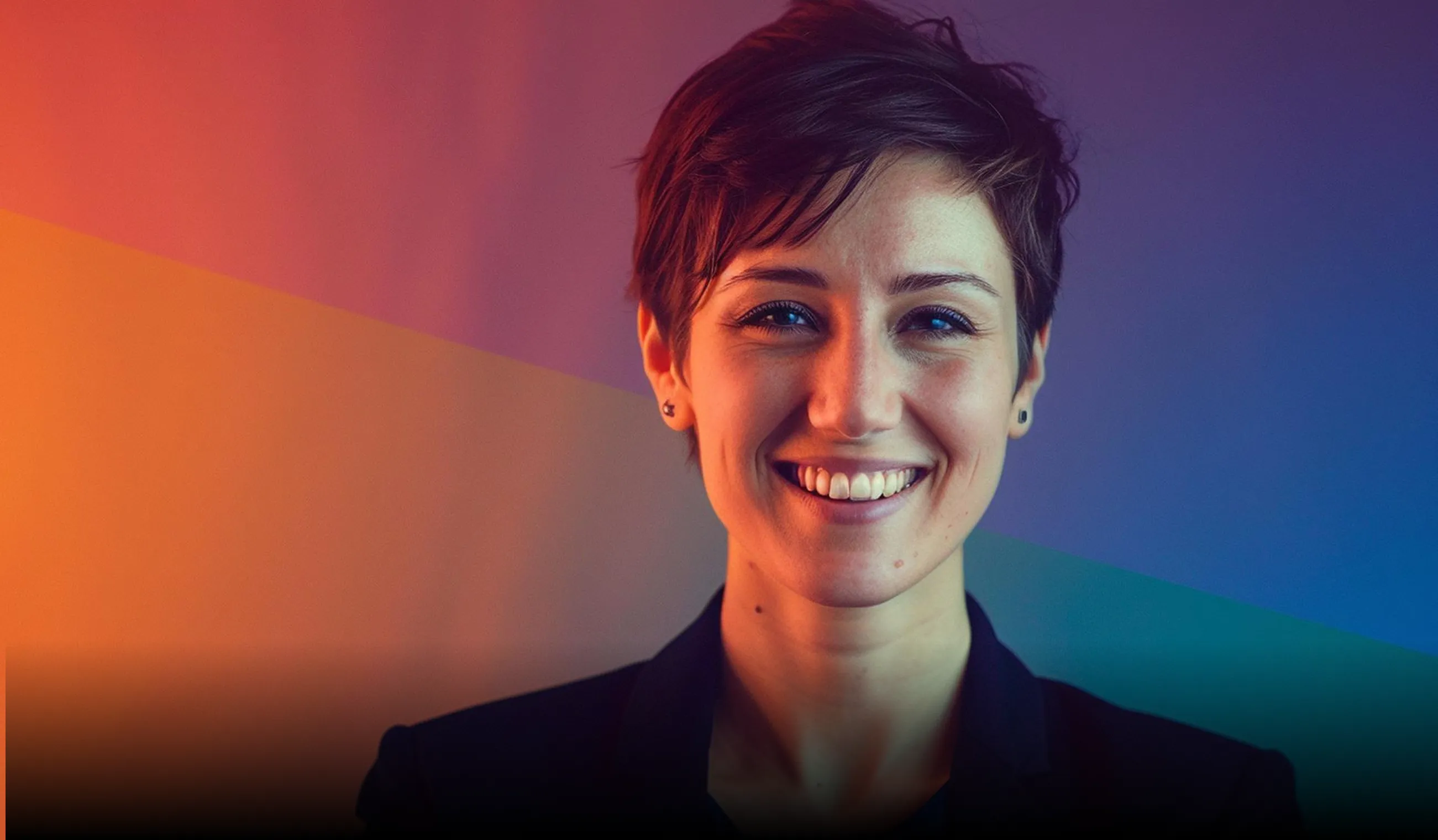 Portrait of a smiling woman with short dark hair against a dark background