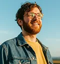 Portrait of a bearded man in a denim jacket against a blue sky