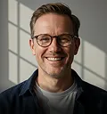 Portrait of a smiling man with glasses in a gray shirt