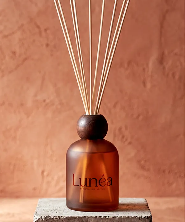 Reed diffuser bottle with sticks on a warm terracotta background