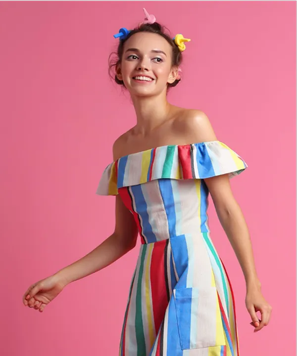 Woman in colorful striped dress posing against a dark background