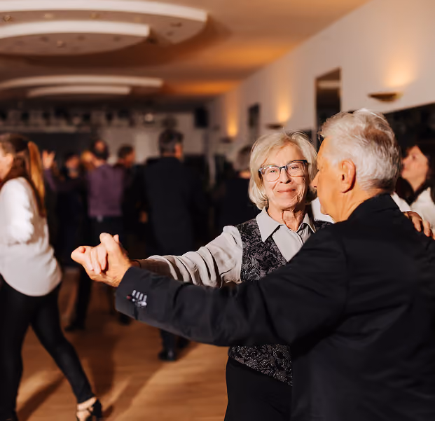 Ein älteres Ehepaar übt gemeinsam Tanzschritte in einer Tanzschule.