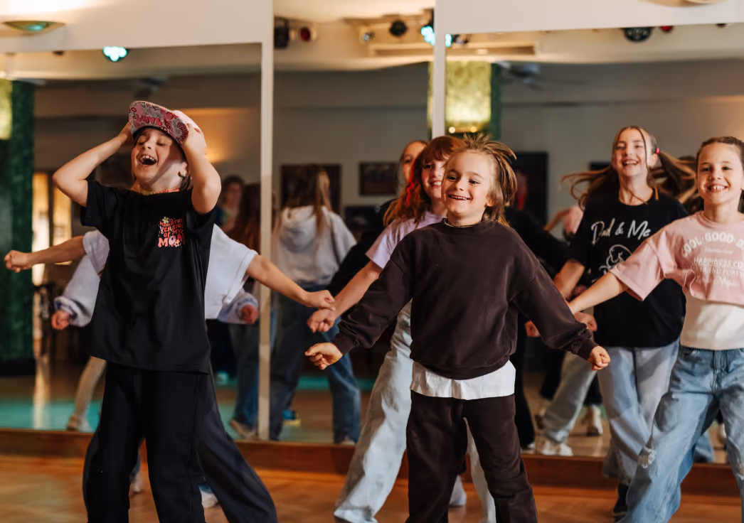 Mehrere Kinder tanzen in einer Probestunde, lachen & haben Spaß.