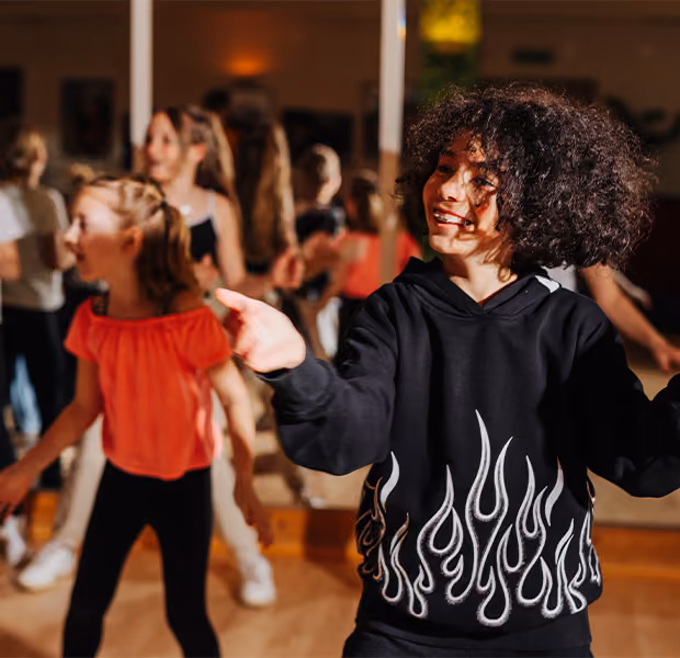Drei Kinder posieren in einer Tanzpose.