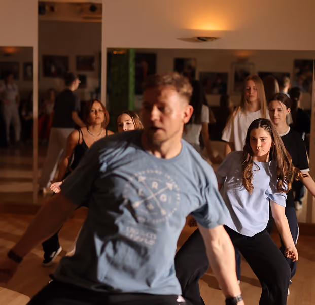 Ein Tanzlehrer zeigt Jugendlichen Hip-Hop Tanzschritte.