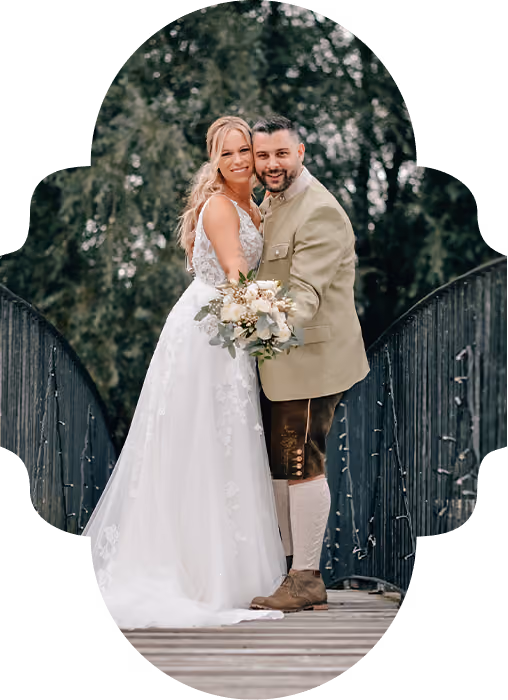 Hochzeitspaar steht auf einer Brück und hält sich in den Armen.