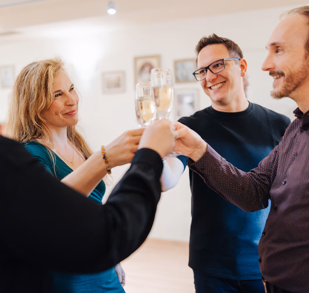 Mehrere Mitglieder der Tanzschule Dietrich stoßen mit einem Glas Sekt an.