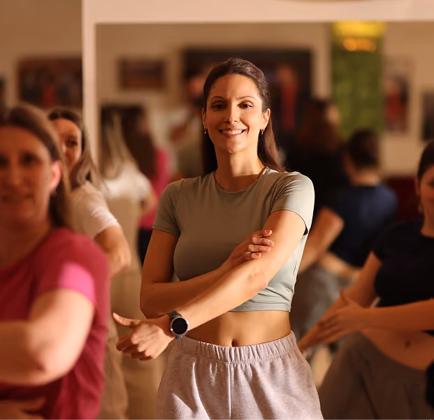 Eine Tanzlehrerin zeigt einige Hip-Hop Tanzschritte und lächelt.