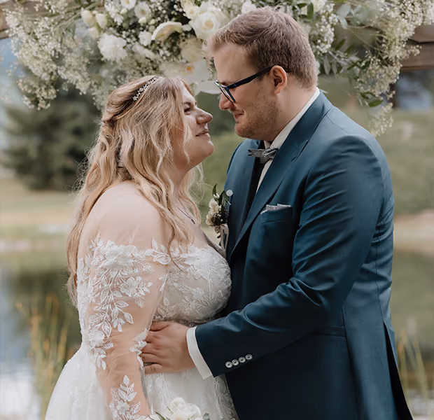 Hochzeitspaar steht sich im Freien gegenüber.