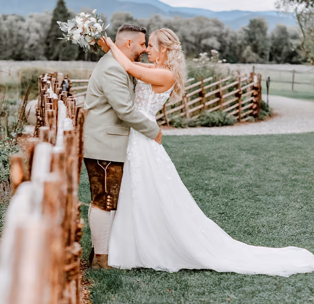 Ein Hochzeitspaar steht im Freien und küsst sich.