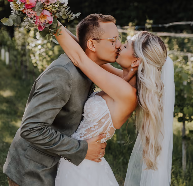 Ein Hochzeitspaar liegt sich in den Armen und küsst sich.