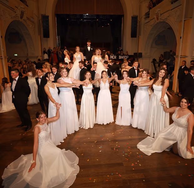 Verschiedene Tanzpaare in einem Saal bei einem festlichen Balltanz.