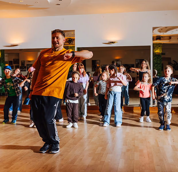 Jörd Dietrich macht einer Gruppe Kinder ein paar Hip-Hop Tanzschritte vor.