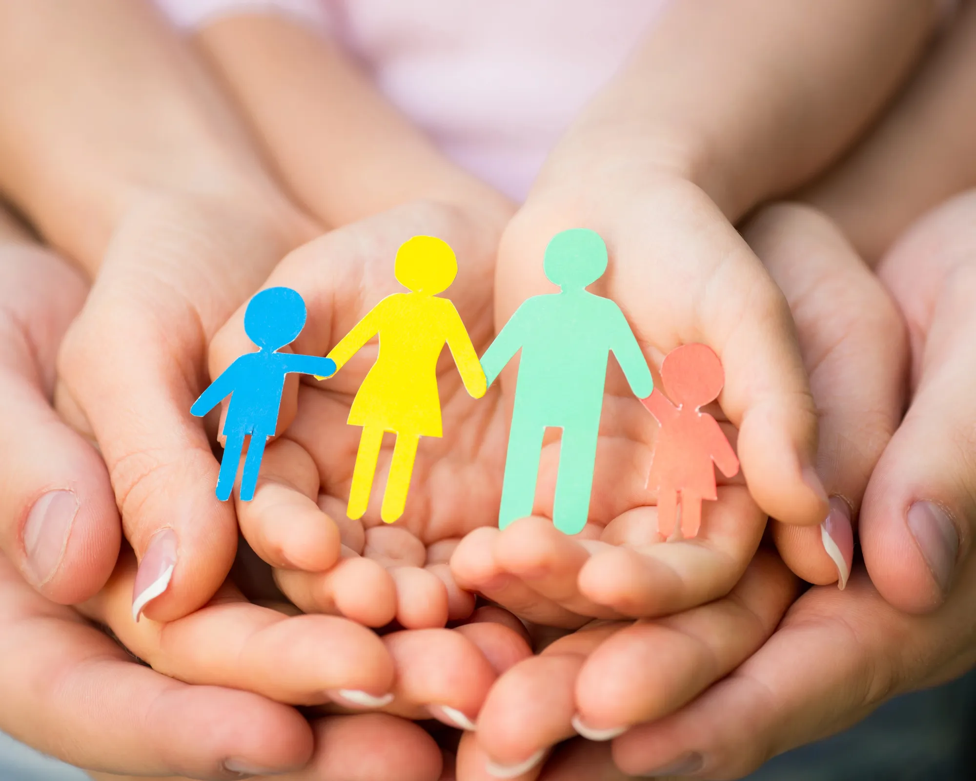 Adult and child hands holding colorful paper figures of a family