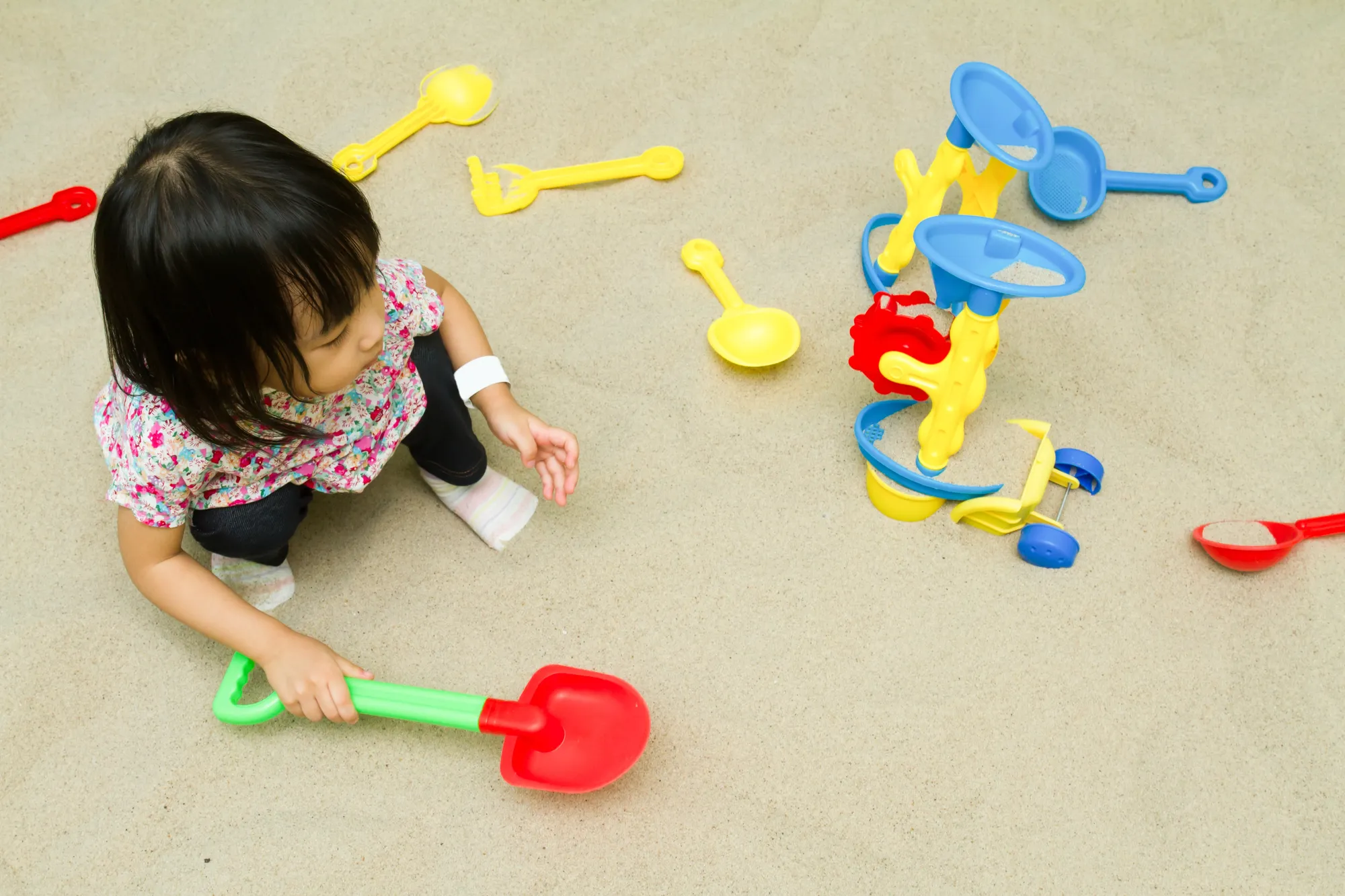 Child playing with a shovel and sand wheel in a sandbox