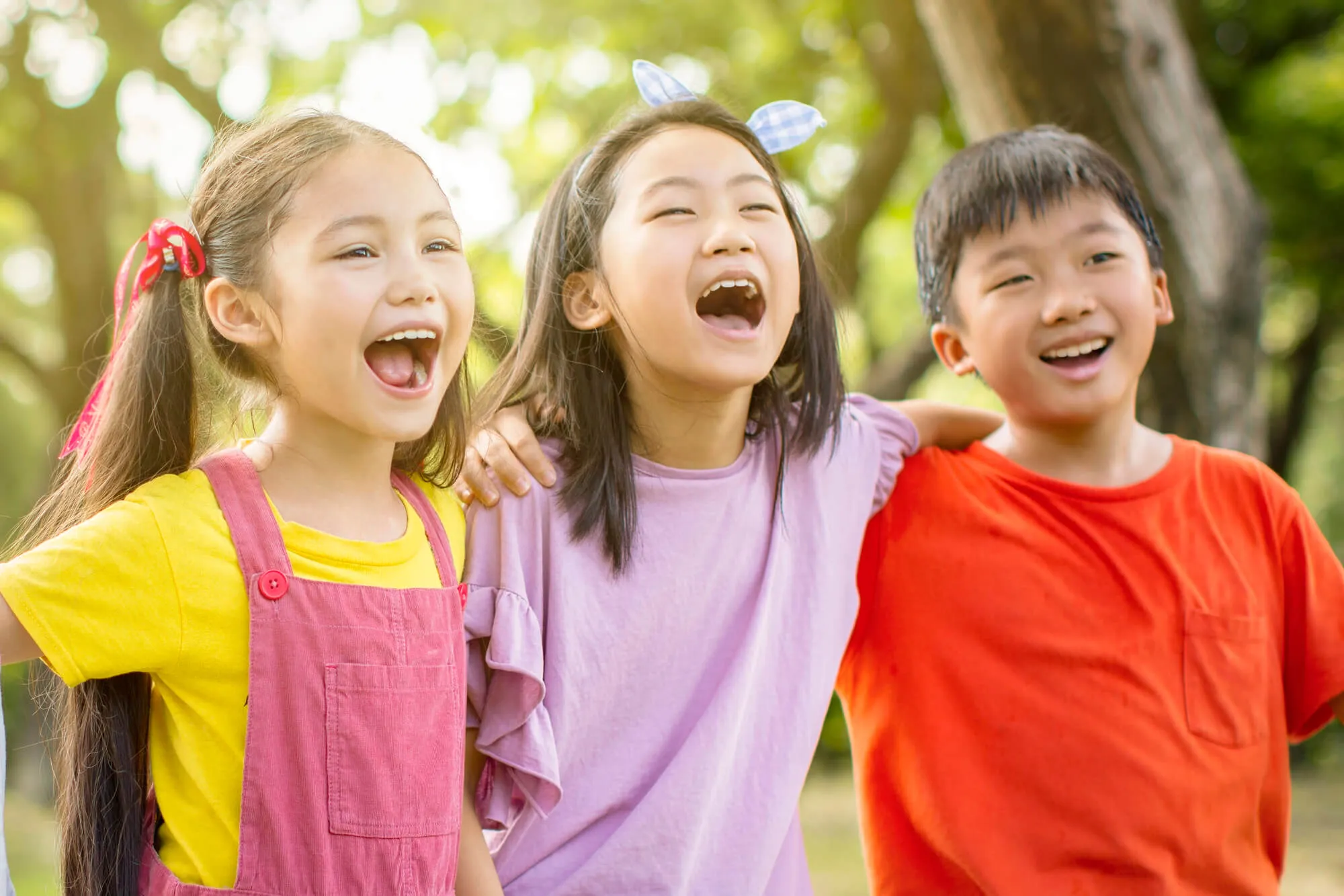 Three children laughing together outdoors