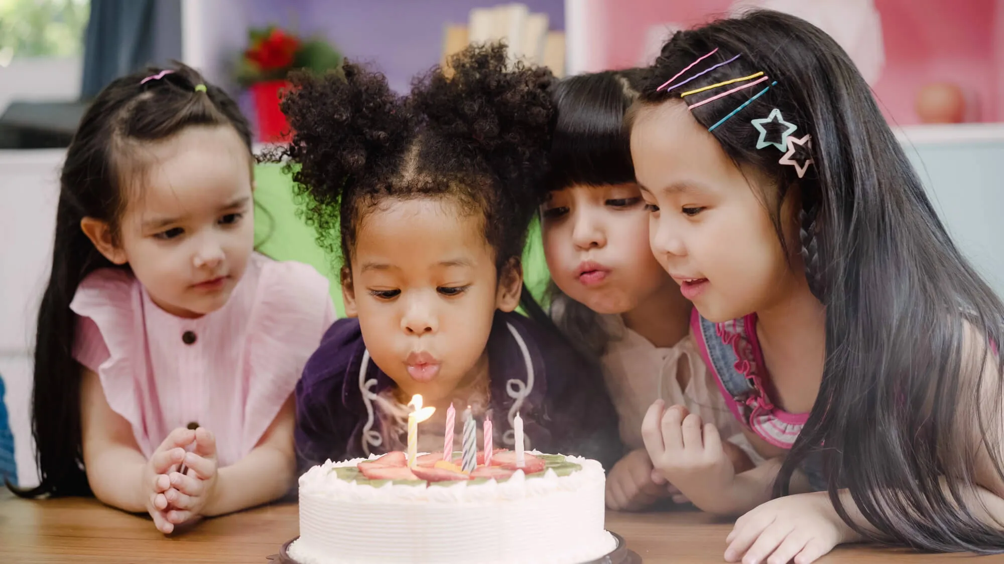 Girls blowing out candles together on a birthday cake