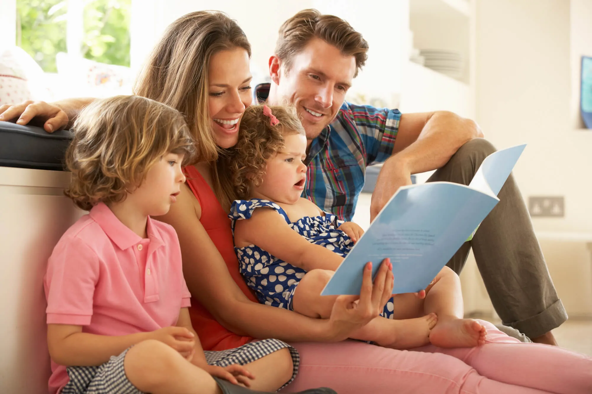 Family reading a picture book together on a sofa