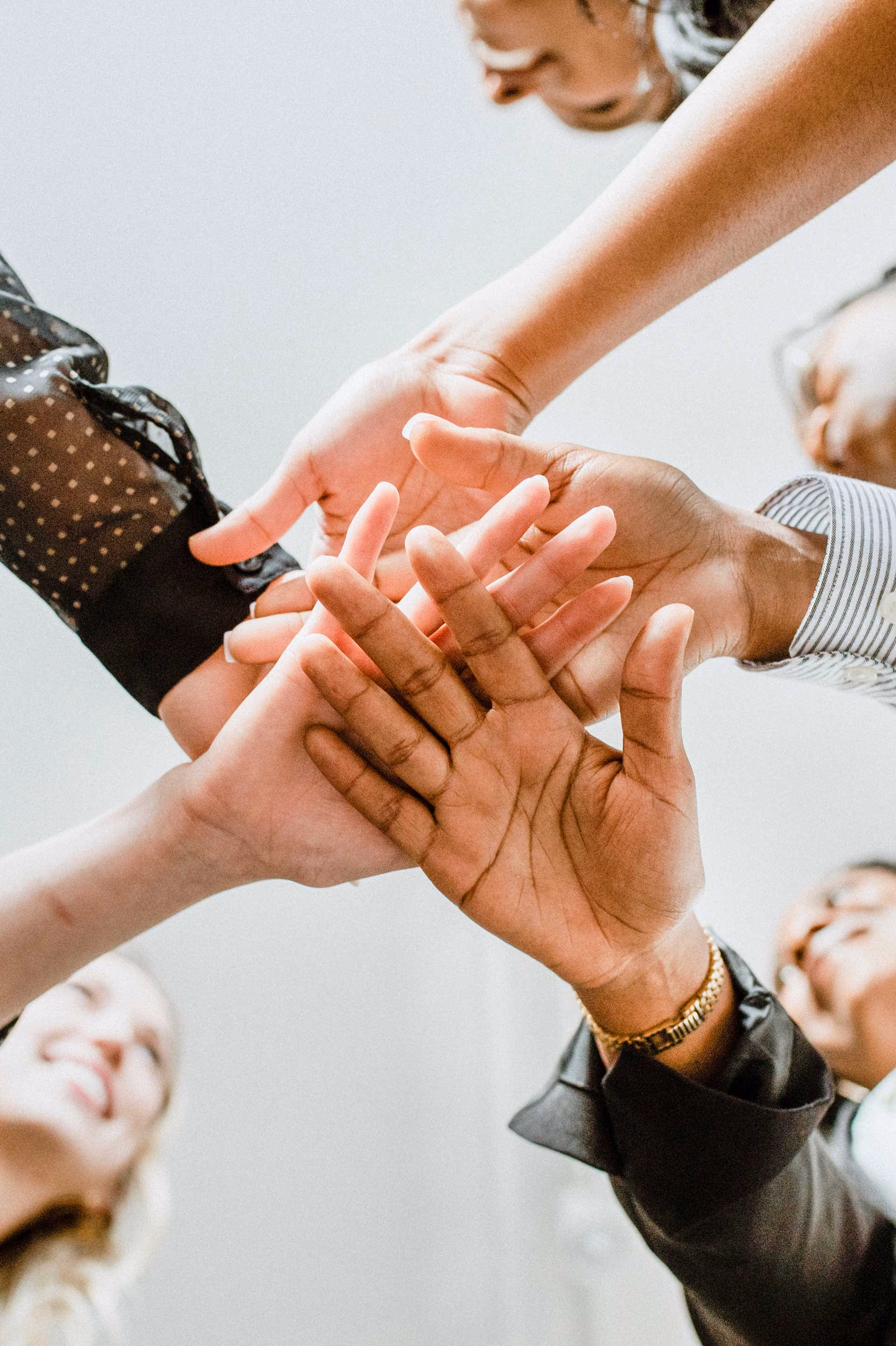 Diverse group of people joining hands together in a team gesture symbolizing unity.