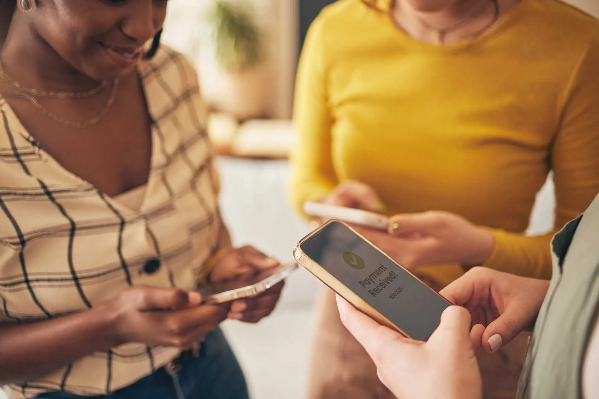 Three people holding smartphones with one showing a 'Payment Received' confirmation screen.