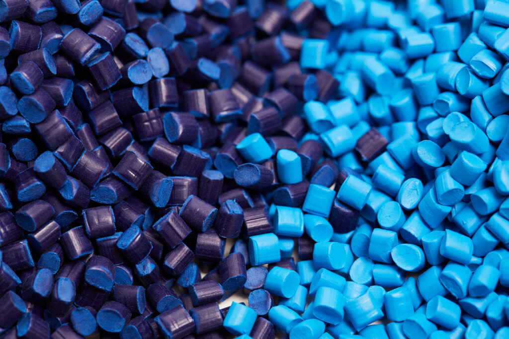 Close-up of small plastic pellets in purple, light blue, dark blue, and yellow colors.