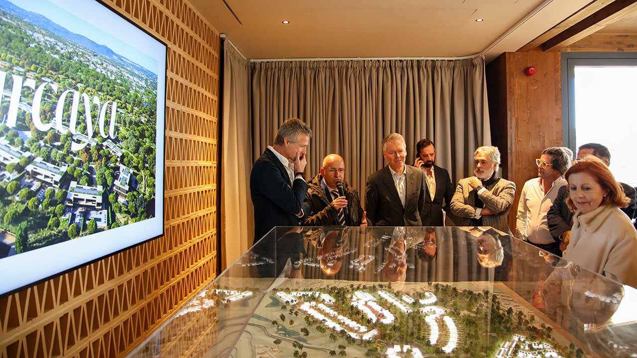Group of people observing and discussing a detailed architectural model in a conference room.