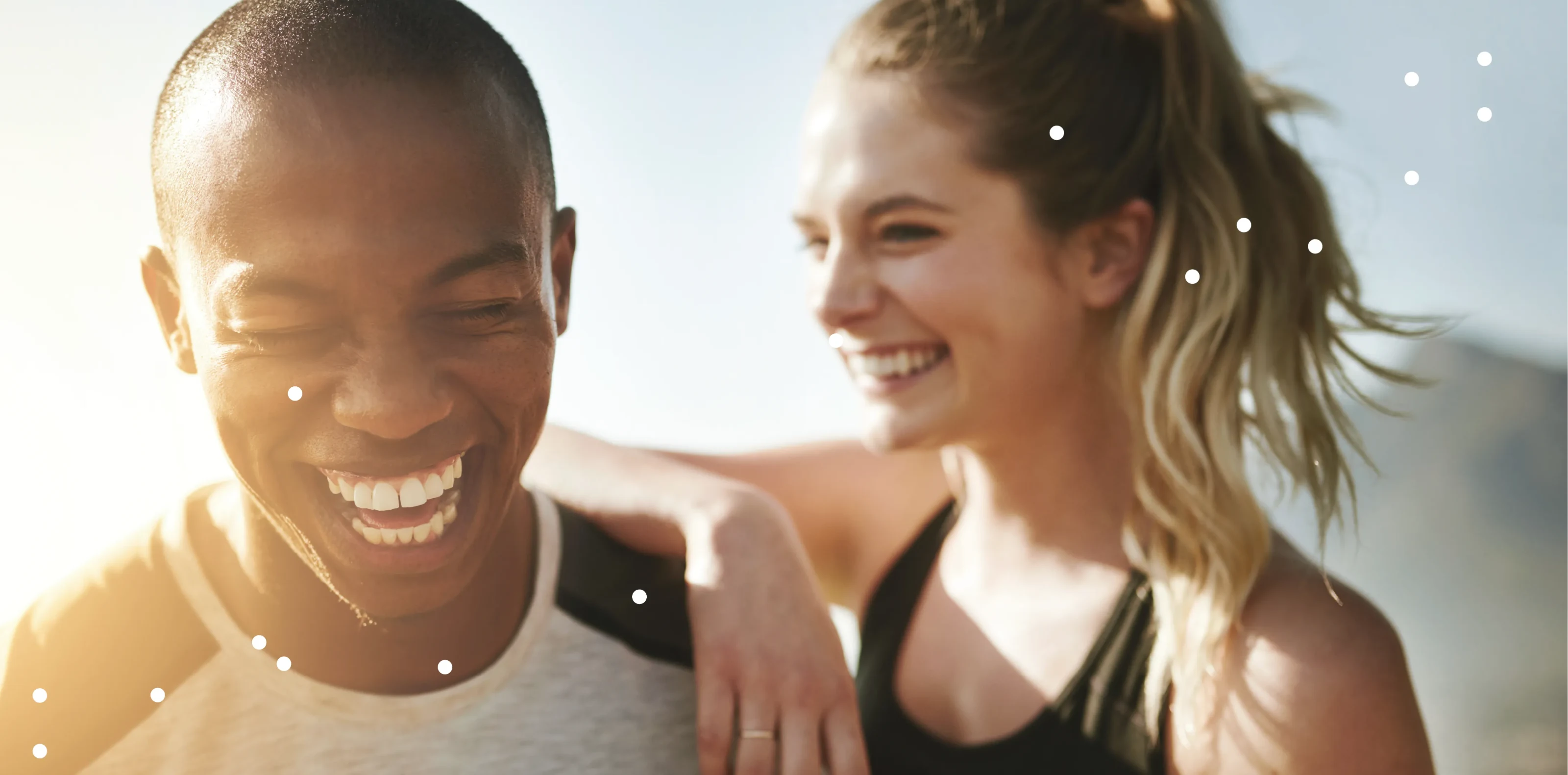 Two friends laughing together outdoors in the sun