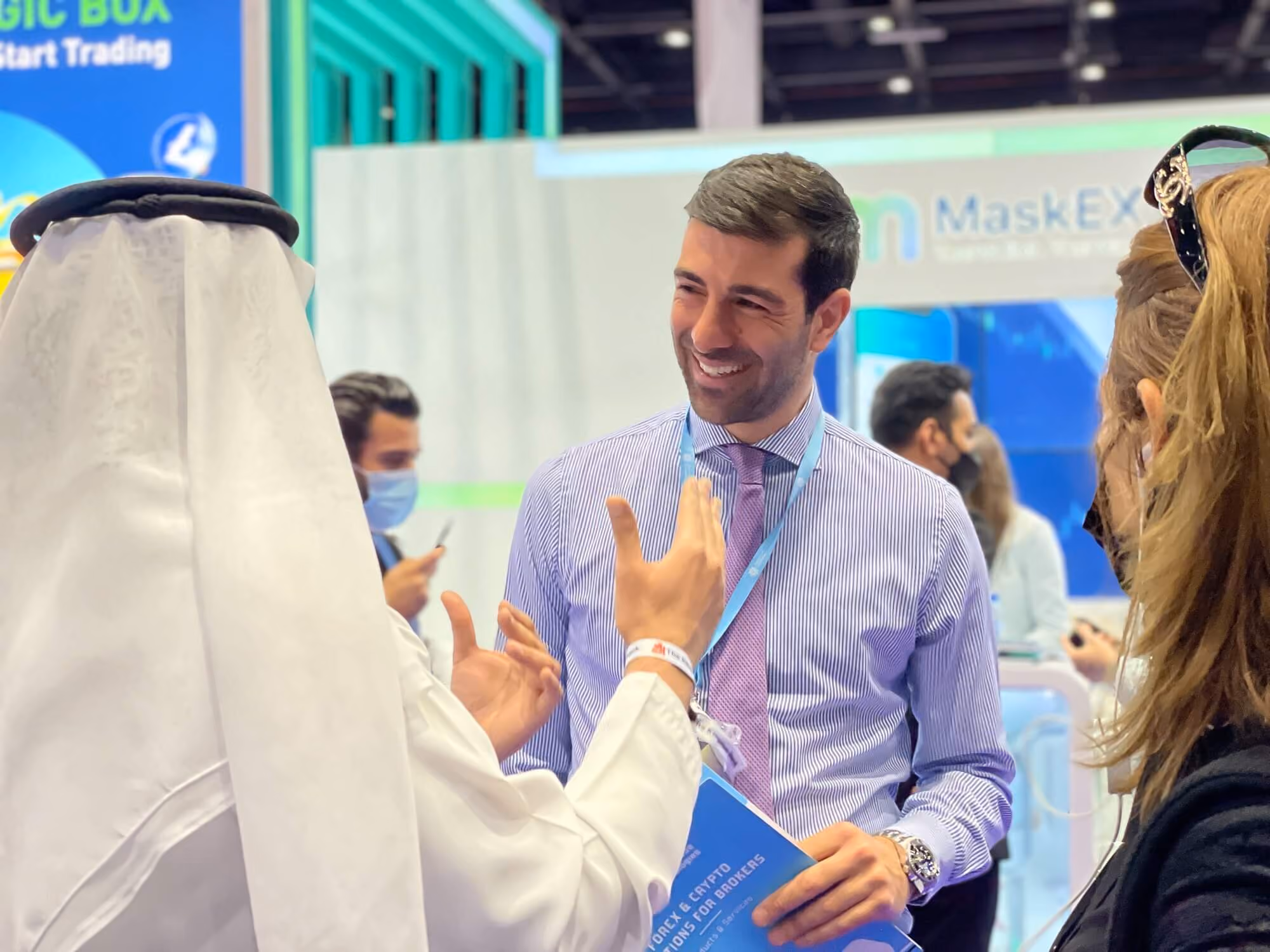 A Match-Prime representative in conversation with a visitor in traditional Gulf dress at an industry expo.