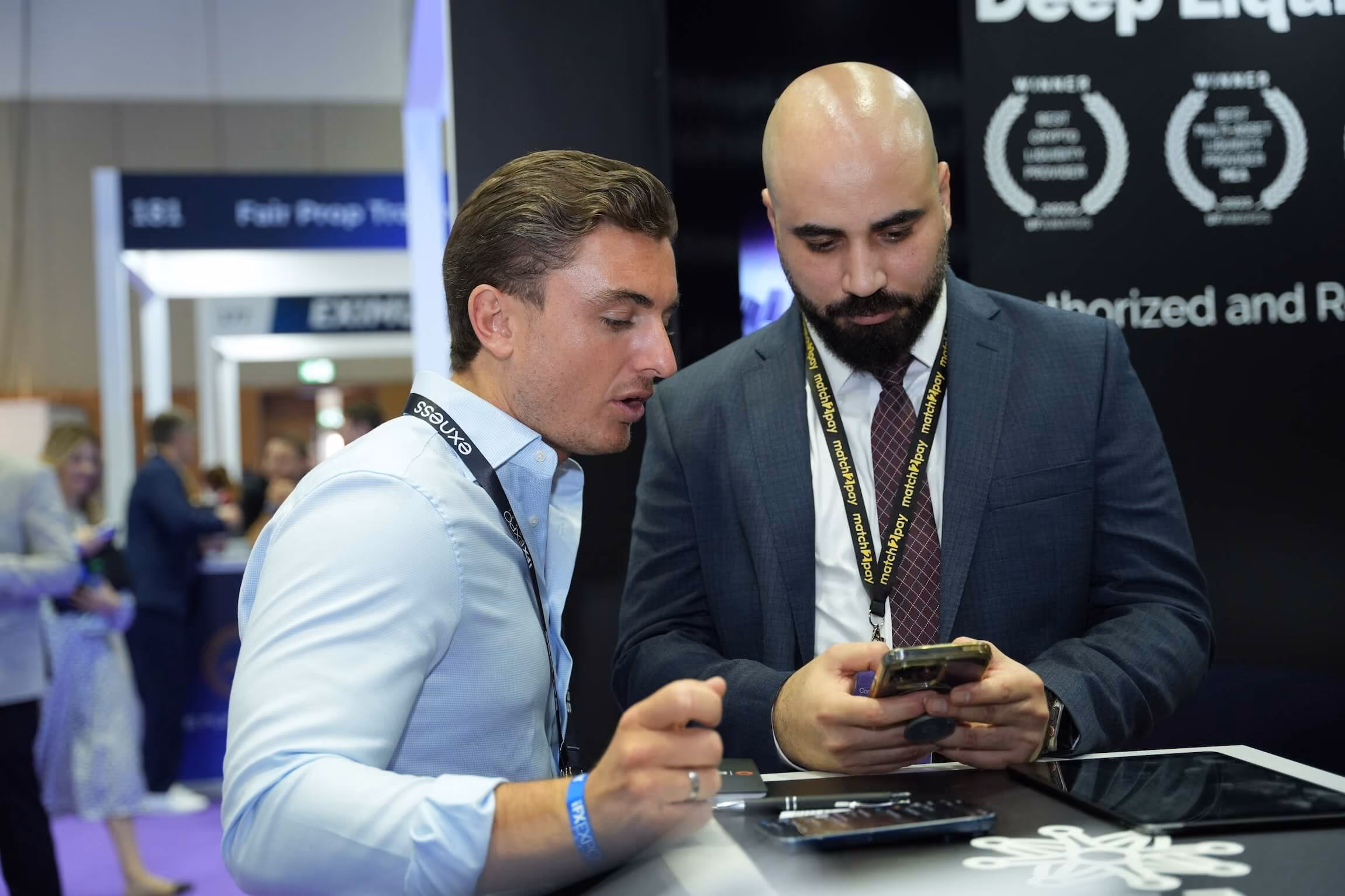 A Match-Prime team member talking with a broker across the company's stand at an industry expo.