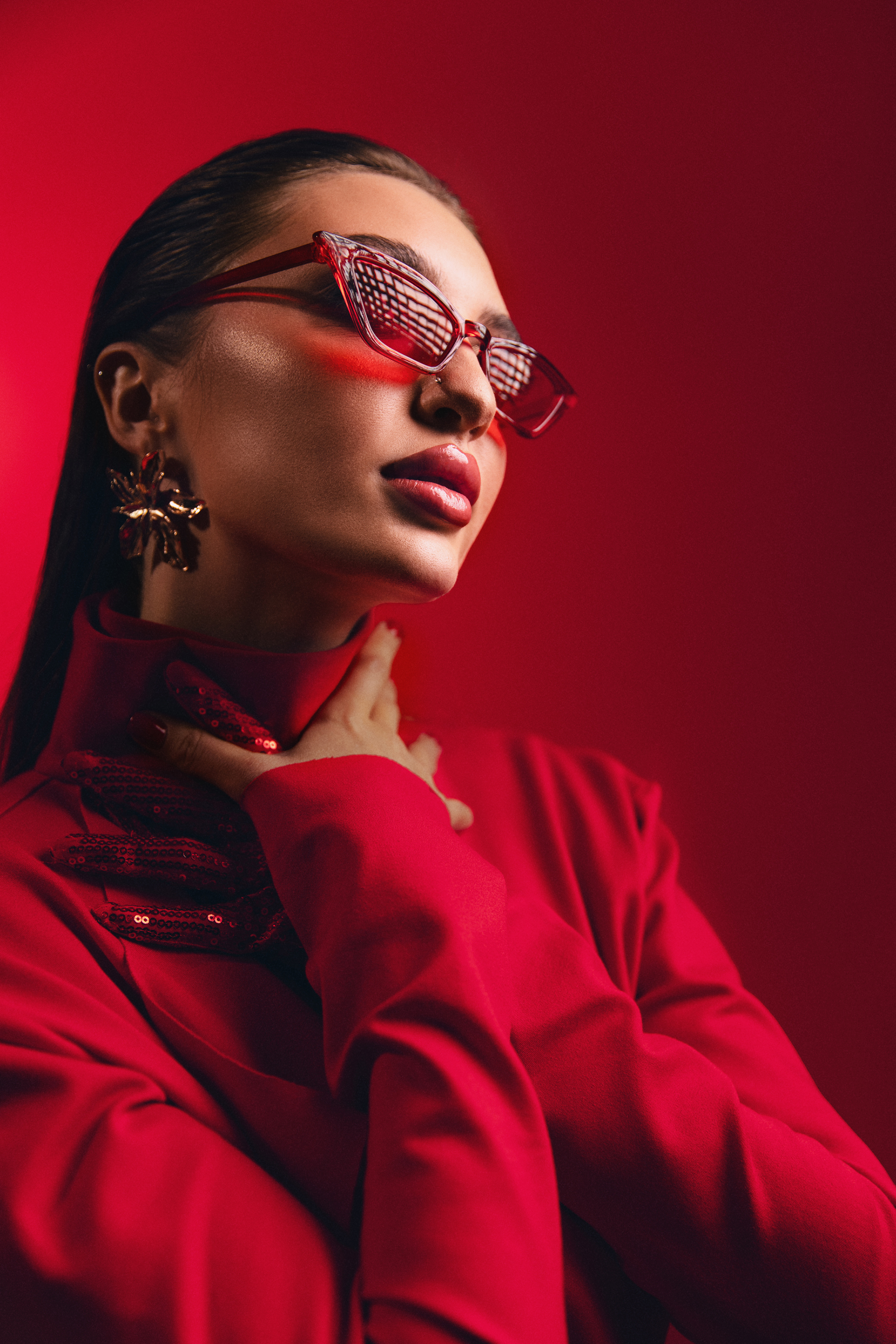 Editorial fashion portrait of a woman in red with statement sunglasses