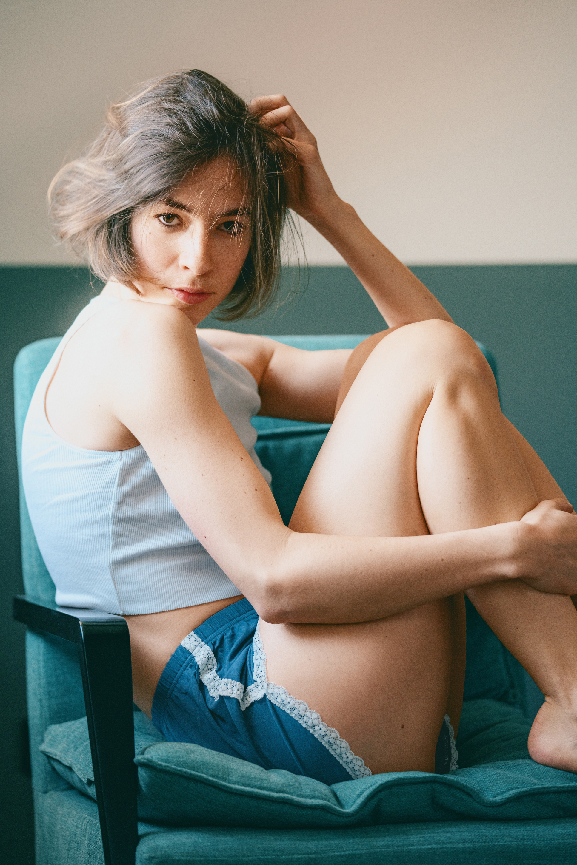Natural lifestyle portrait of a woman sitting in a teal chair