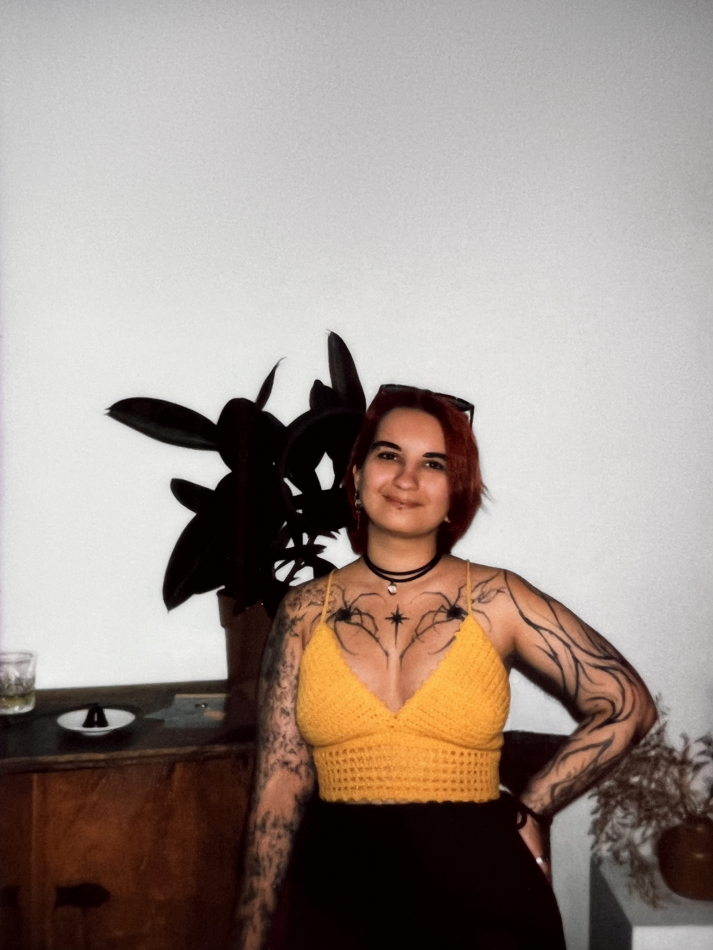 Portrait of a woman with red hair and tattoos wearing a yellow top indoors