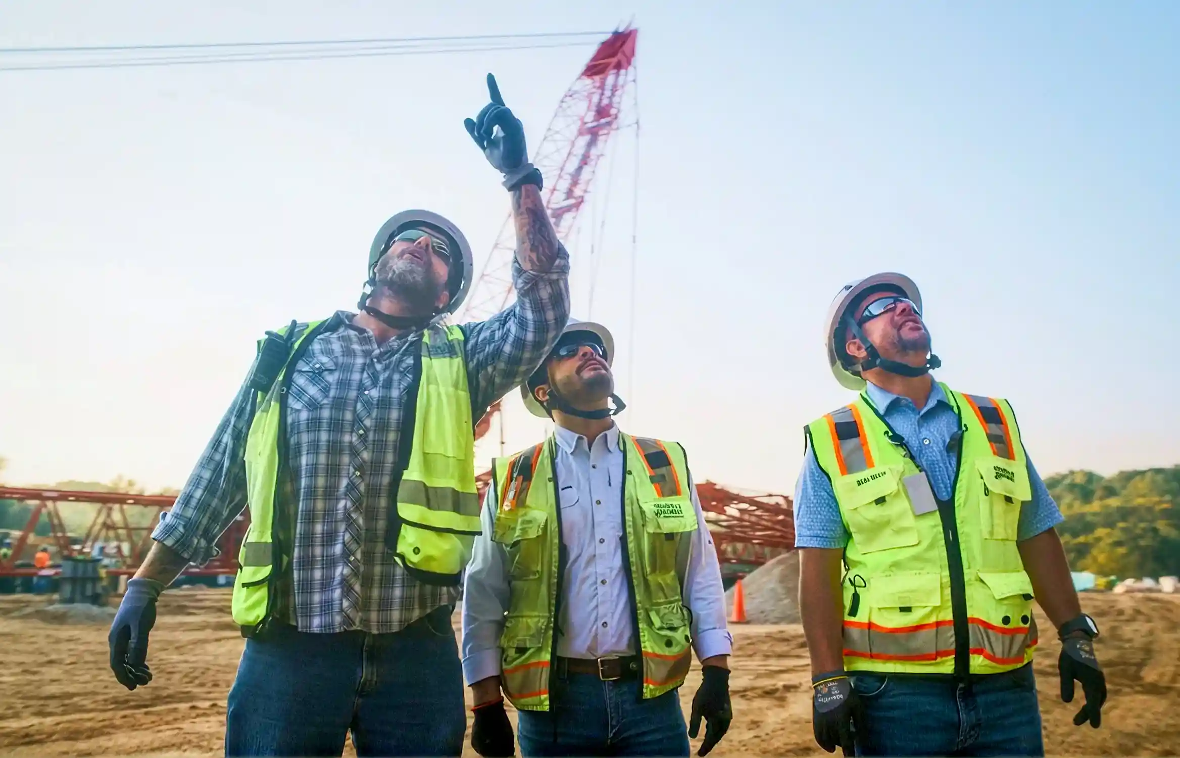 Three Brasfield and Gorrie workers looking up at a crane on a jobsite