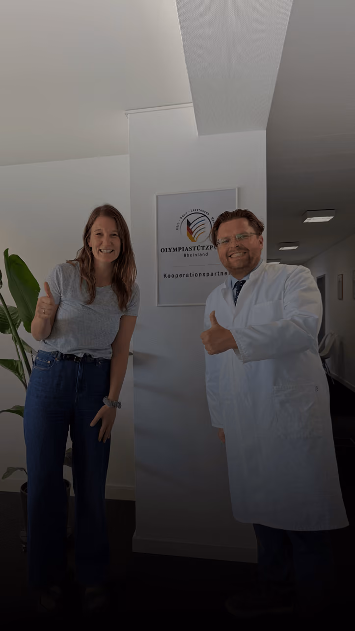 Smiling man and woman showing thumbs up in a cluttered room, woman wears black jacket with Rümpel Welt logo.