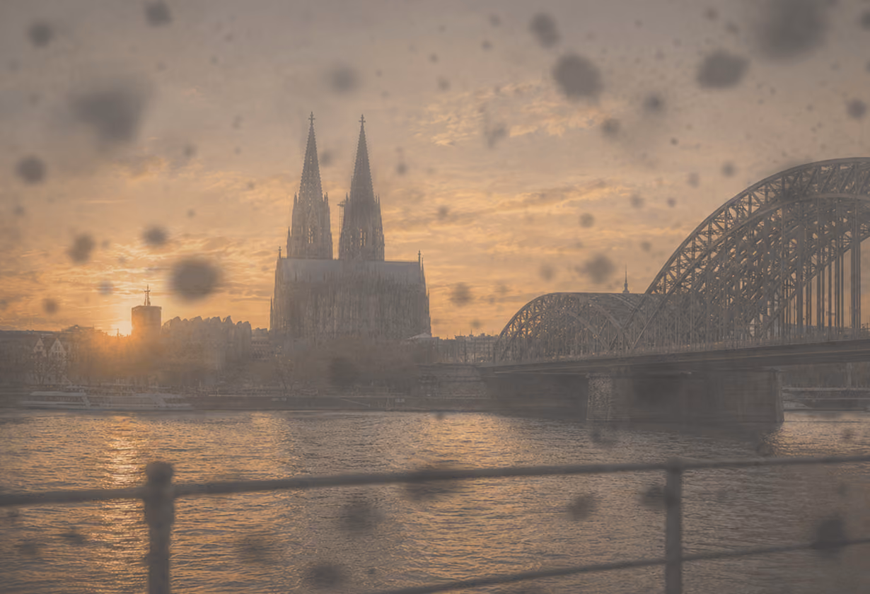 Kölner Dom bei Sonnenuntergang, Regen auf Fenster, Hohenzollernbrücke rechts.