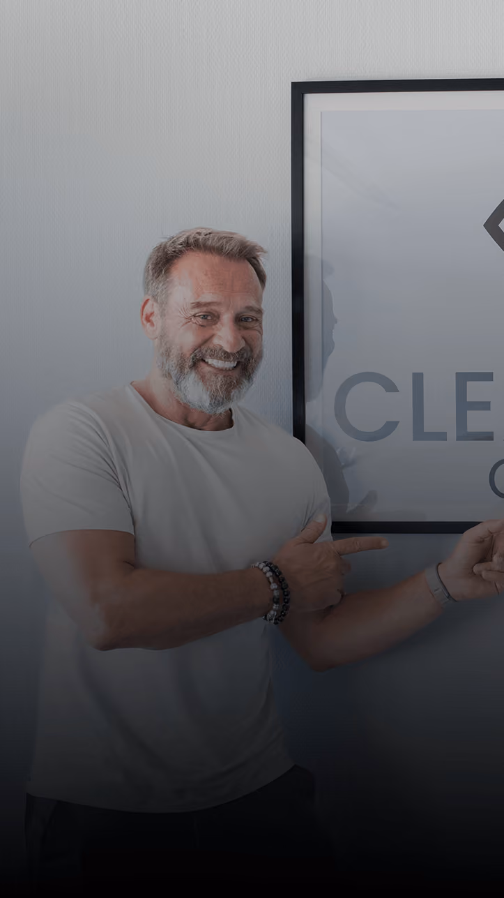 Two smiling men in work clothes posing for selfie in an empty room, one showing a thumbs-up.