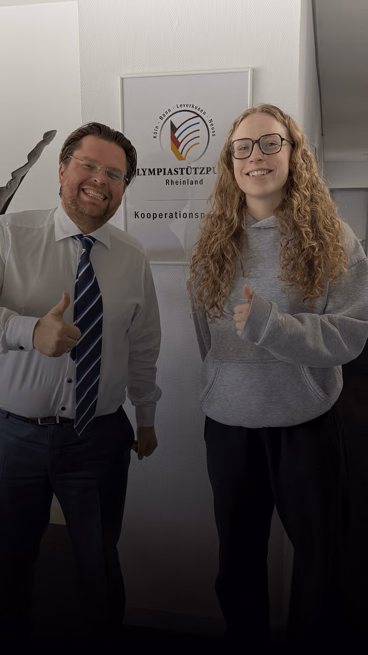 Two women smiling indoors, giving thumbs up; one wears a black jacket with RÜMPEL WELT logo.