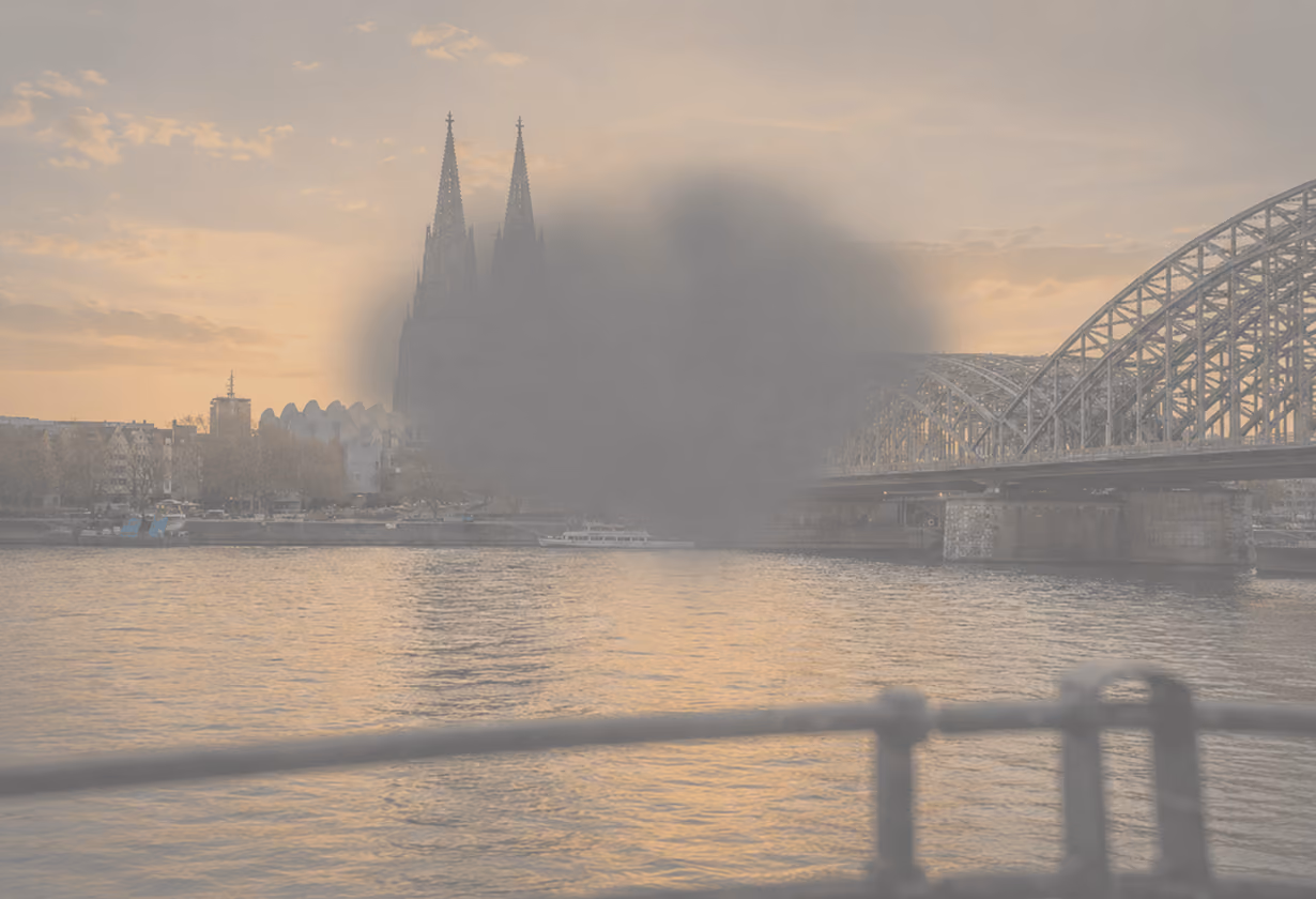 Kölner Dom und Hohenzollernbrücke im Sonnenuntergang mit großem Rauchwolke.