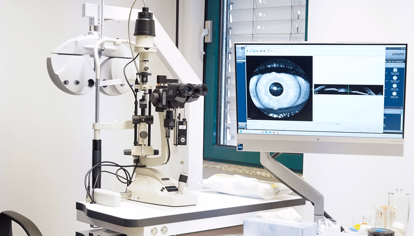 Augenuntersuchungsequipment mit Spaltlampe und Monitor zeigt detailliertes Augenbild, moderne medizinische Diagnosetechnologie.