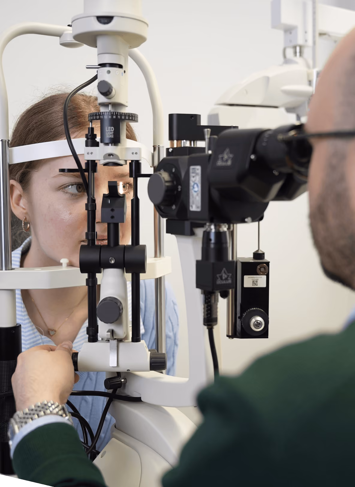 Augenuntersuchung mit Spaltlampe; Optiker untersucht Patientin; Fokus auf Auge und Gerät.