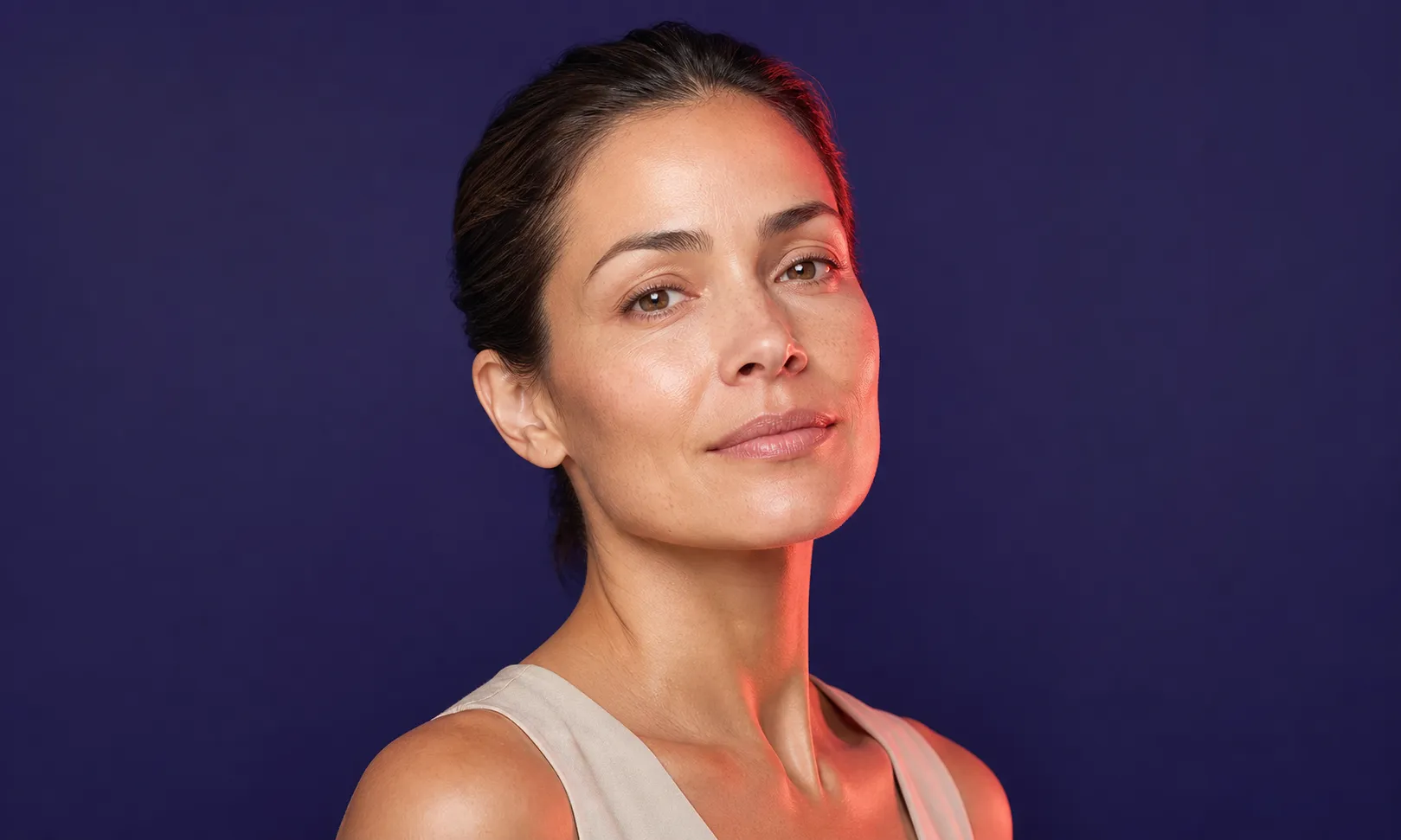 Portrait d'une femme avec un regard confiant sur fond bleu foncé.