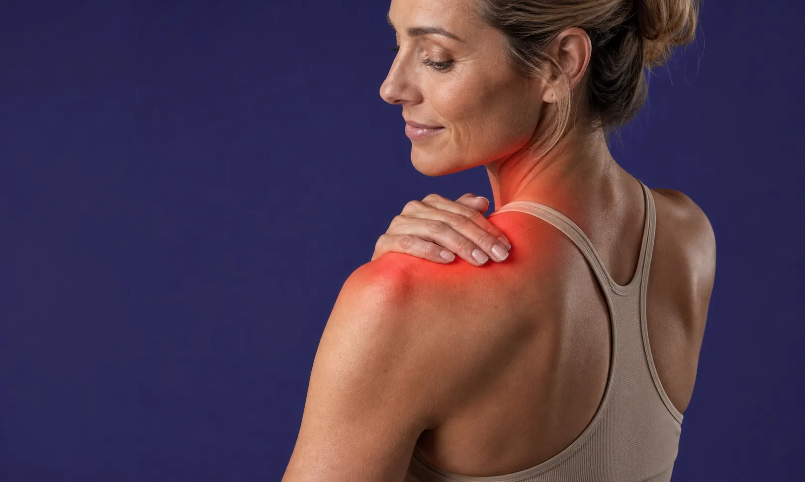 Femme touchant son épaule rouge, indiquant une douleur ou une tension musculaire.