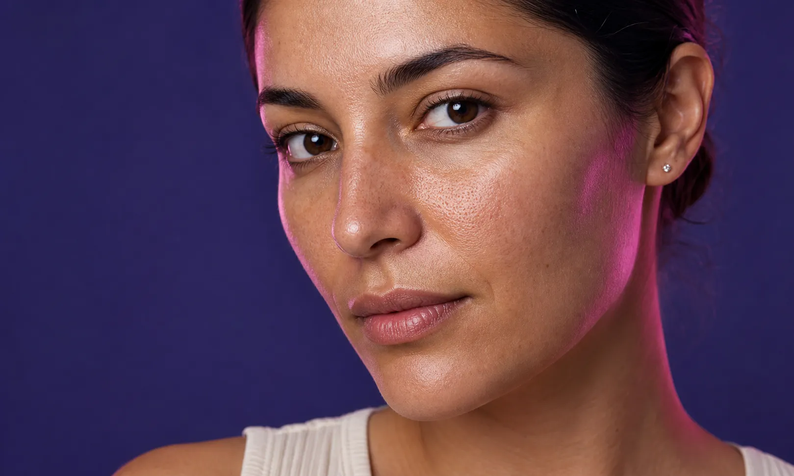 Gros plan sur le visage d'une femme avec un teint naturel et des pores visibles sur une peau saine.
