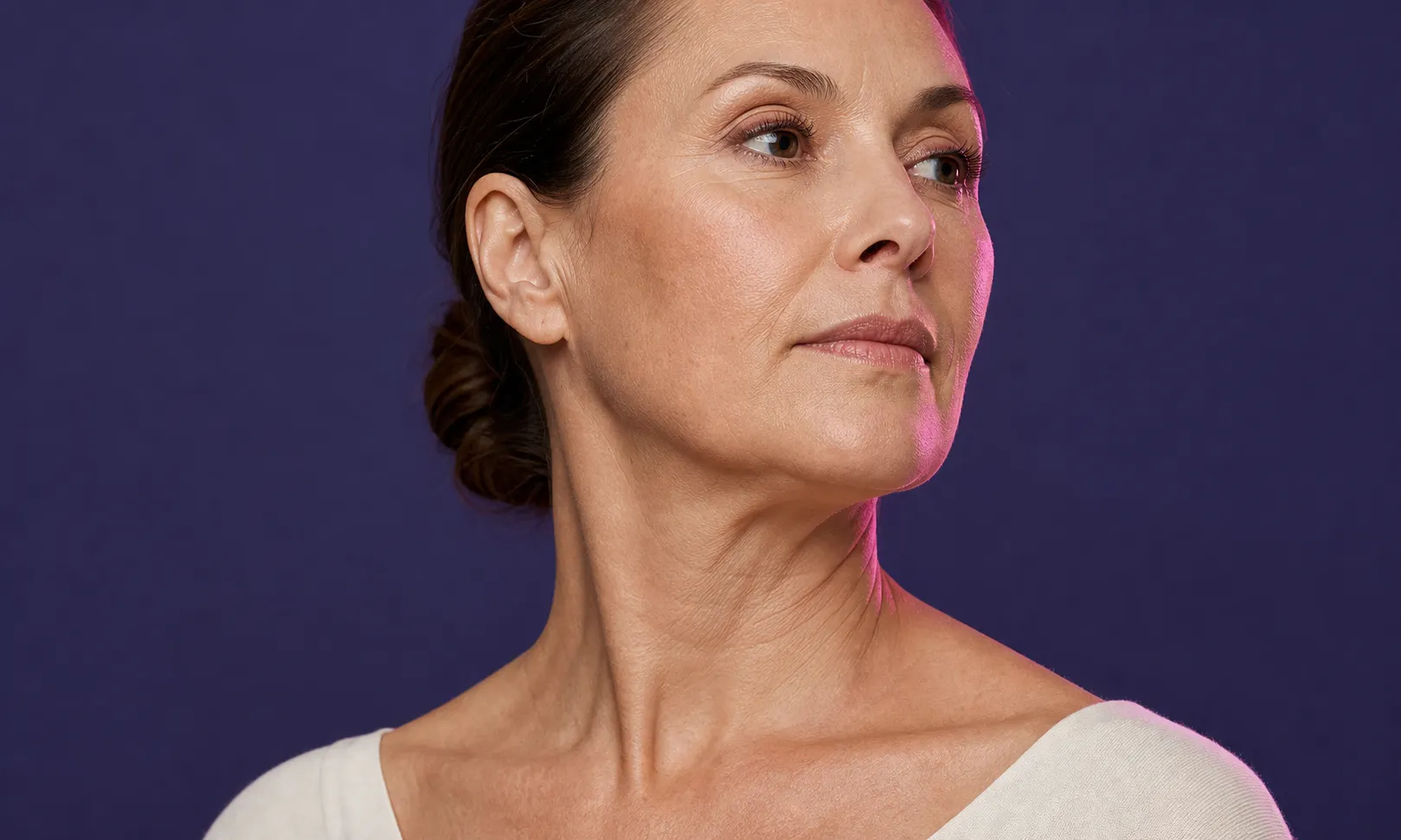 Portrait d'une femme mûre regardant vers la droite avec un fond violet uni.