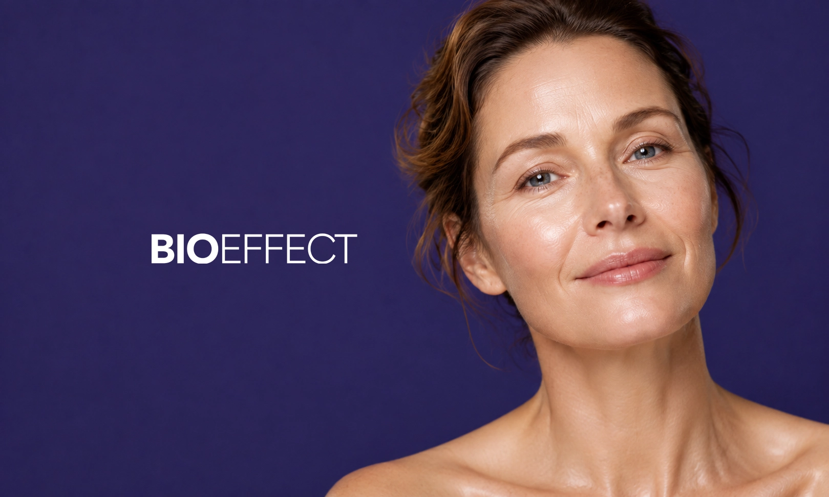 Portrait d'une femme aux cheveux châtains clairs et peau lumineuse souriant légèrement devant un fond violet, avec le texte BIOEFFECT en blanc à gauche.